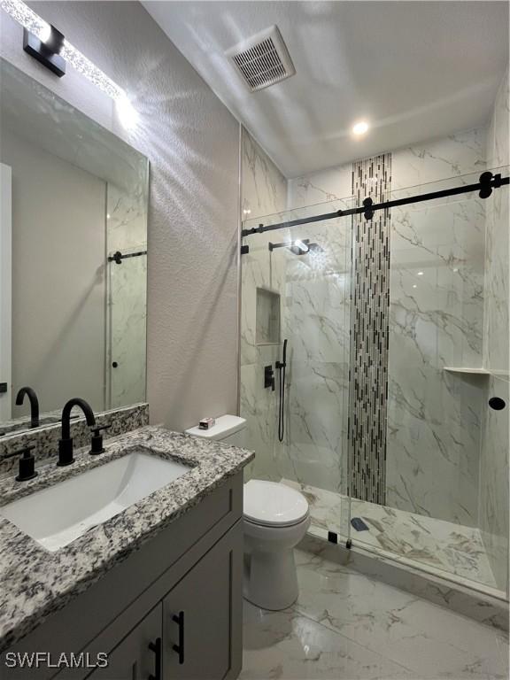 bathroom with walk in shower, vanity, and toilet