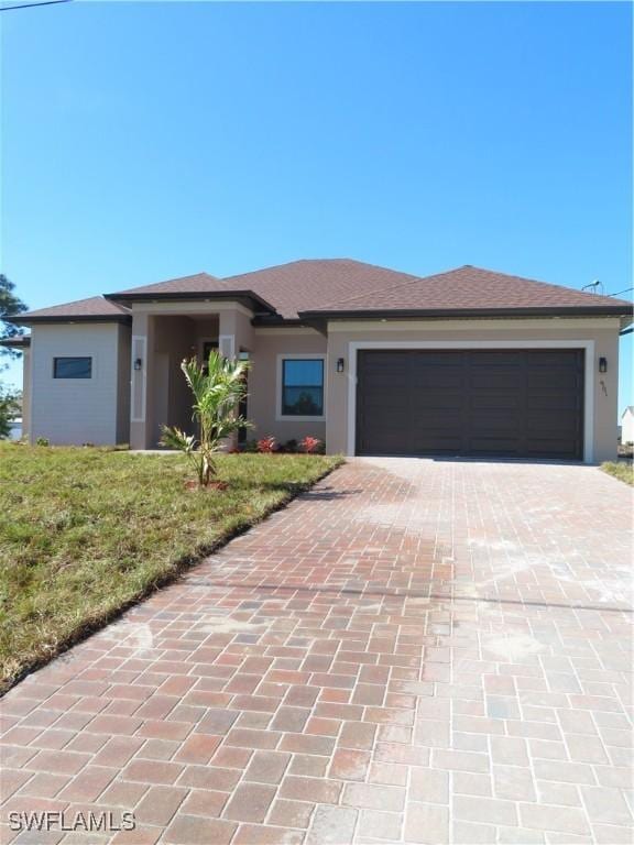 prairie-style home with a garage and a front lawn