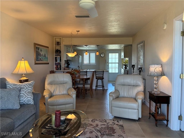 tiled living room with ceiling fan and built in shelves