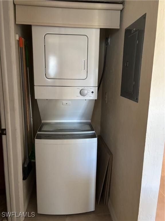 laundry room featuring electric panel and stacked washer / drying machine