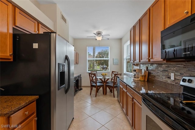 kitchen with light tile patterned floors, dark stone countertops, tasteful backsplash, appliances with stainless steel finishes, and ceiling fan