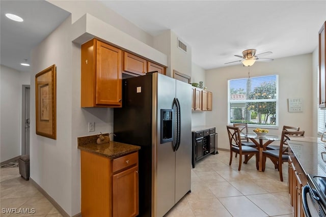 kitchen featuring dark stone countertops, ceiling fan, light tile patterned floors, stove, and stainless steel fridge