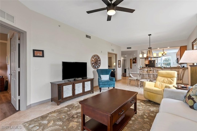 tiled living room featuring ceiling fan with notable chandelier