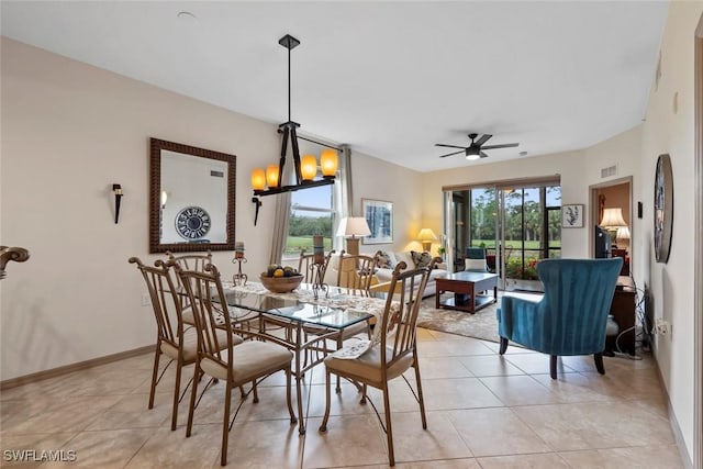 tiled dining room with ceiling fan with notable chandelier