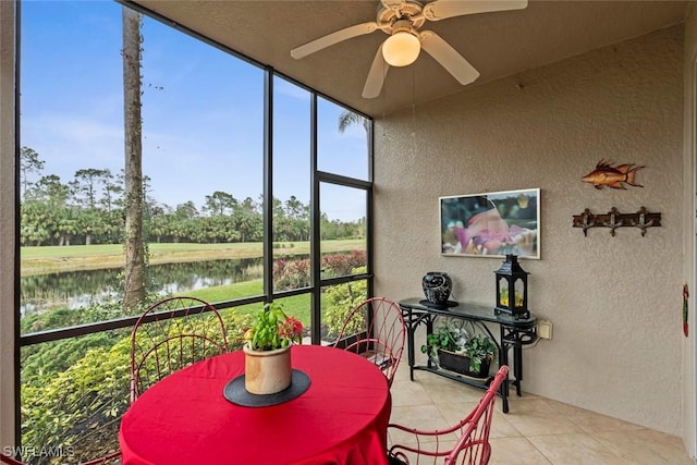 sunroom / solarium featuring ceiling fan and a water view