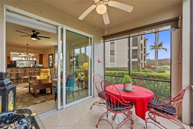 sunroom featuring ceiling fan with notable chandelier