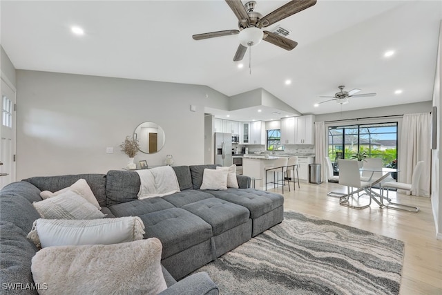 living room featuring ceiling fan, light hardwood / wood-style flooring, and vaulted ceiling