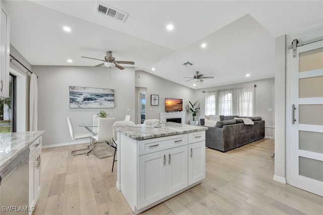 kitchen with white cabinetry, ceiling fan, a barn door, and a center island