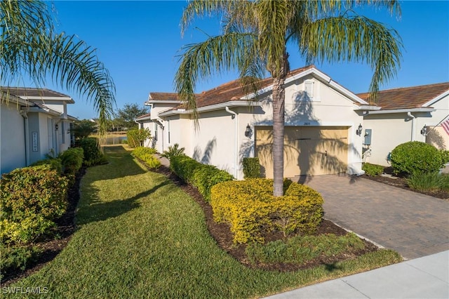 view of side of home featuring a garage, decorative driveway, a lawn, and stucco siding