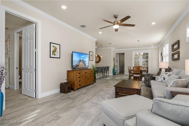 living room with ceiling fan with notable chandelier and crown molding