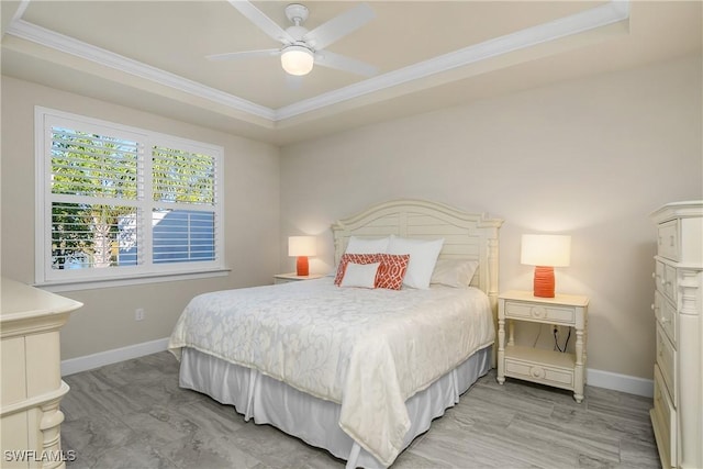 bedroom with ceiling fan, a tray ceiling, and crown molding