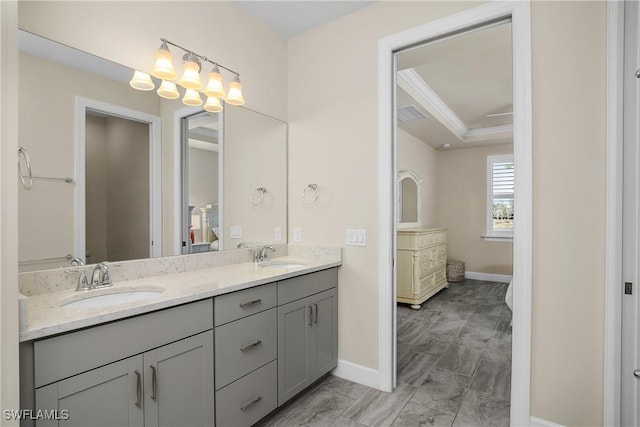 bathroom featuring double vanity, crown molding, a raised ceiling, and a sink