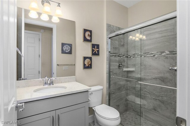 bathroom featuring vanity, toilet, and a shower with door