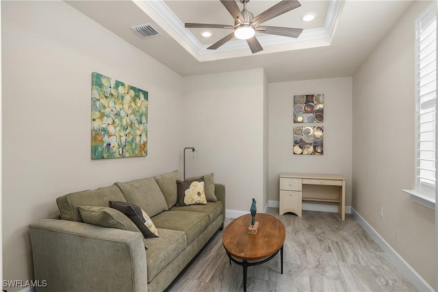 living room featuring ceiling fan, a wealth of natural light, a tray ceiling, and ornamental molding