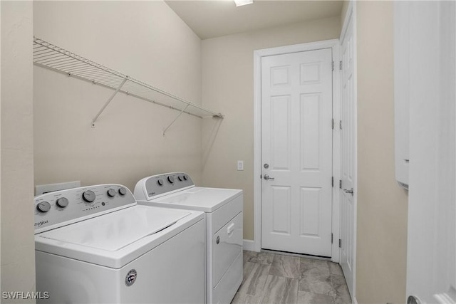 washroom with laundry area, washer and clothes dryer, and baseboards