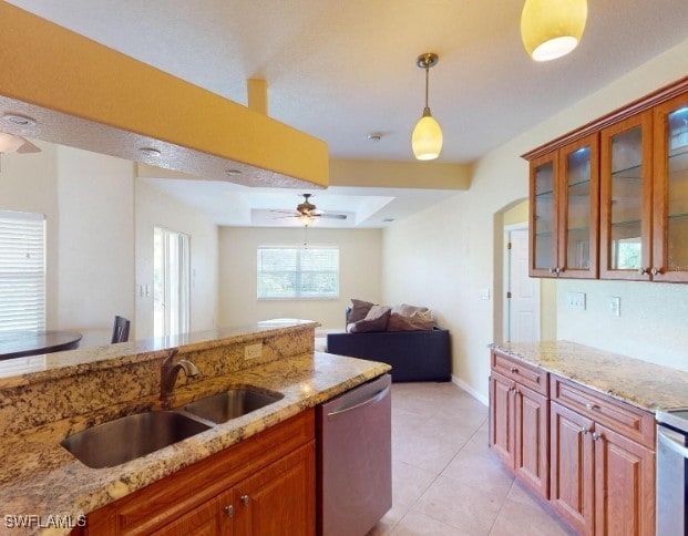 kitchen with light stone countertops, dishwasher, sink, pendant lighting, and light tile patterned floors