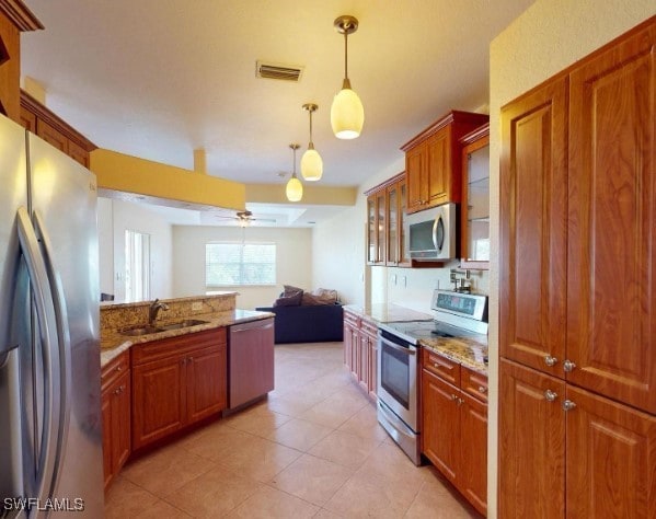 kitchen with ceiling fan, sink, hanging light fixtures, stainless steel appliances, and light stone counters