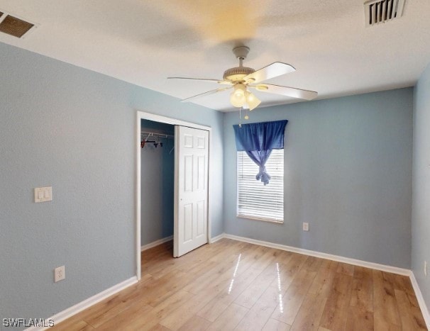 unfurnished bedroom featuring ceiling fan, a closet, and light hardwood / wood-style flooring