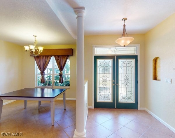 entrance foyer featuring an inviting chandelier, light tile patterned flooring, and french doors