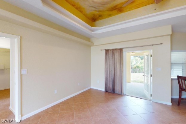 unfurnished room with a raised ceiling and light tile patterned floors