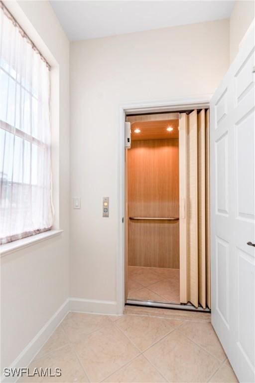 interior space with light tile patterned floors and elevator