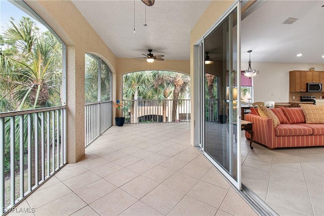 sunroom with ceiling fan with notable chandelier