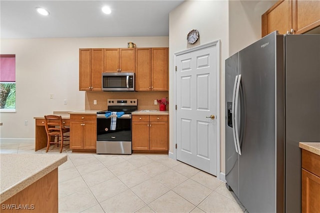 kitchen with appliances with stainless steel finishes, light tile patterned floors, and backsplash