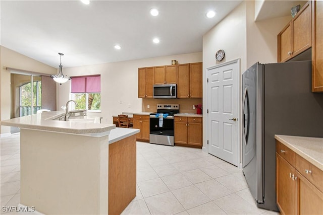 kitchen with appliances with stainless steel finishes, pendant lighting, sink, light tile patterned floors, and a center island with sink