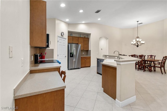 kitchen featuring sink, hanging light fixtures, stainless steel appliances, vaulted ceiling, and a chandelier