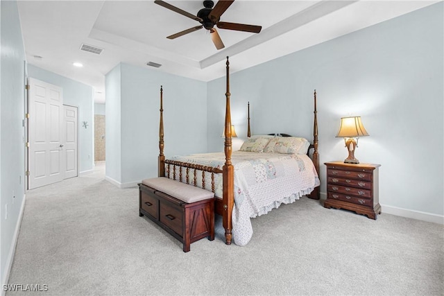 bedroom featuring a raised ceiling, light carpet, and ceiling fan