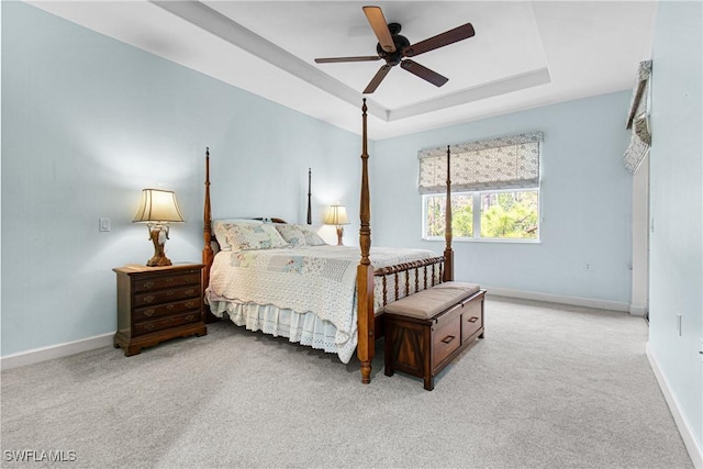 carpeted bedroom with ceiling fan and a tray ceiling