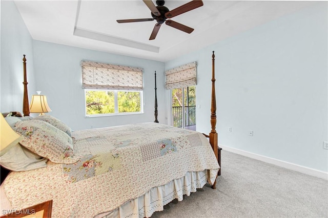 carpeted bedroom with ceiling fan, a tray ceiling, and access to outside