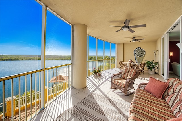 sunroom with ceiling fan and a water view