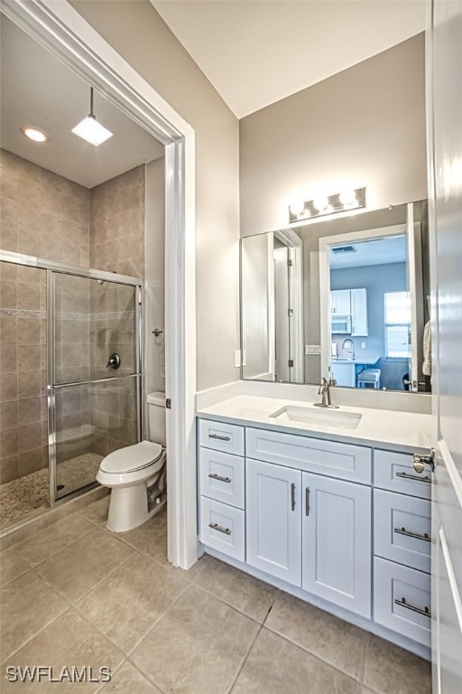 bathroom featuring a shower with door, vanity, tile patterned flooring, and toilet