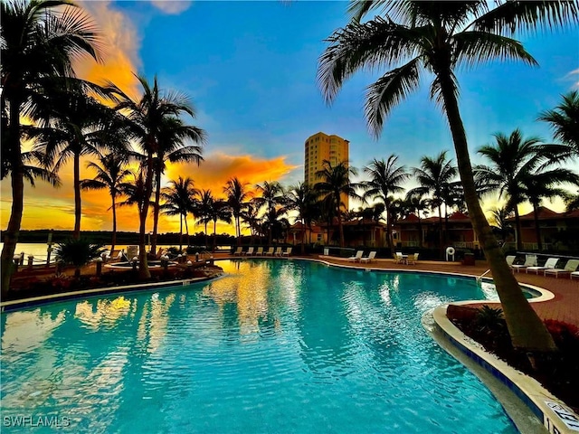 pool at dusk featuring a water view