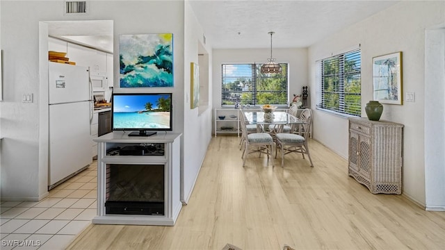 kitchen with white appliances, white cabinets, light wood-type flooring, and hanging light fixtures