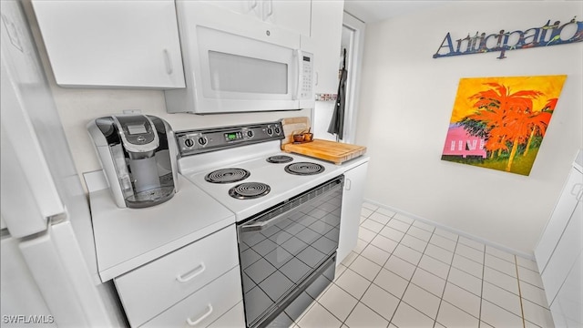 kitchen featuring white appliances, white cabinetry, and light tile patterned flooring