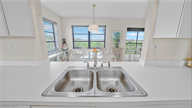 kitchen with sink, pendant lighting, and white cabinetry