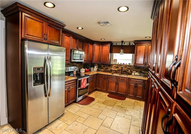 kitchen featuring light stone countertops, appliances with stainless steel finishes, backsplash, and sink