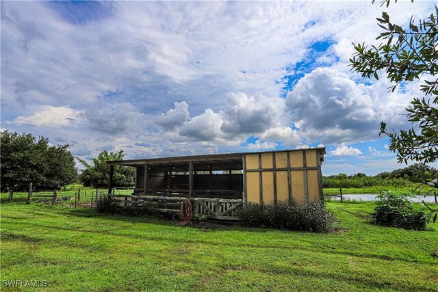 view of outbuilding featuring a rural view, a yard, and a water view