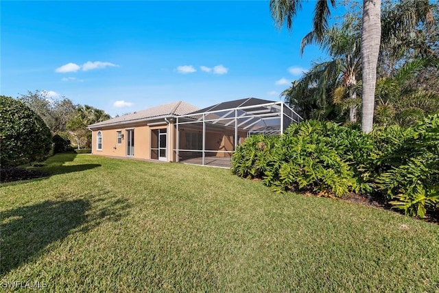 rear view of house with a lanai and a yard