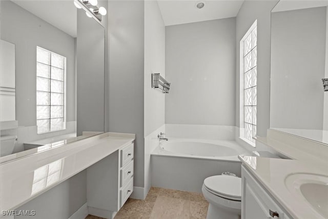 bathroom featuring toilet, a wealth of natural light, a bath, and vanity