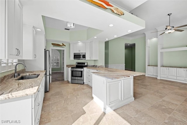 kitchen with light stone countertops, stainless steel appliances, white cabinetry, and sink