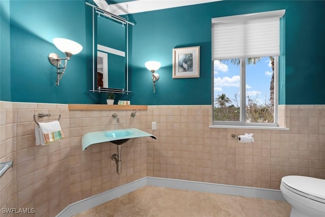 bathroom with a wainscoted wall, tile walls, and toilet