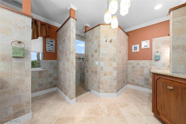 bathroom with a tile shower, tile walls, ornamental molding, and vanity