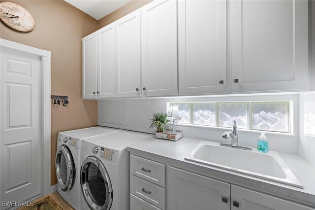 washroom with cabinets, washing machine and clothes dryer, and sink