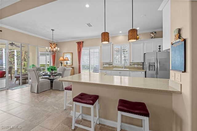 kitchen featuring stainless steel fridge with ice dispenser, pendant lighting, a kitchen bar, sink, and white cabinetry