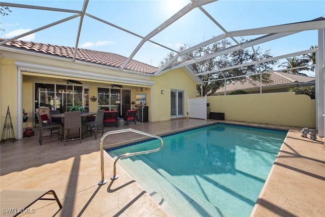 view of swimming pool featuring a patio, ceiling fan, and glass enclosure