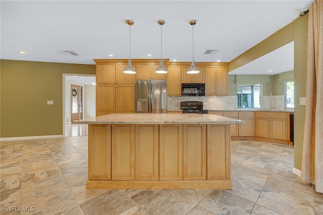 kitchen featuring light stone counters, black appliances, a center island, hanging light fixtures, and backsplash