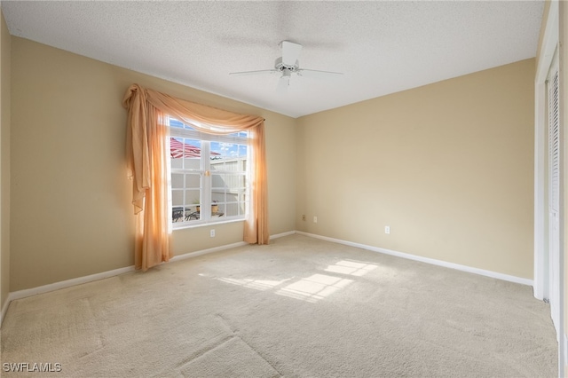 unfurnished room featuring ceiling fan, light colored carpet, and a textured ceiling